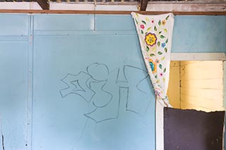 Embroidered cloth hanging on wall of abandoned house