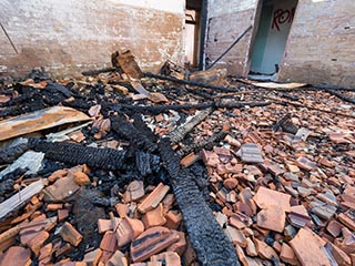 Broken roof tiles and charred timbers on floor of St. John's Orphanage