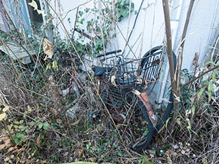 Wrecked bicycle outside abandoned Japanese house