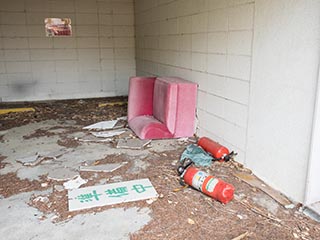 Sofa, fire extinguishers, and sign scattered in carport at Hotel Penguin Village