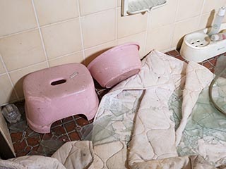 Bathing stool, basin, and debris in bathroom in Motel Akatsuki