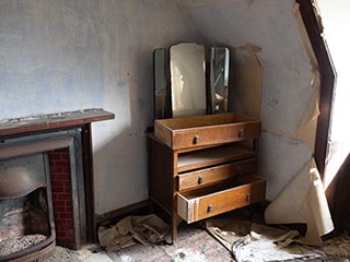 chest of drawers and mirror in abandoned bedroom