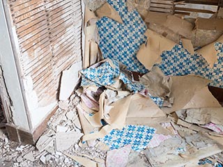 plaster debris and torn wallpaper on floor