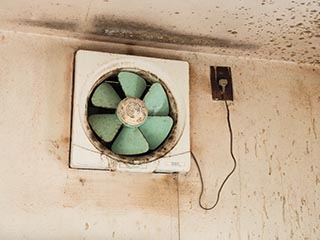 Extractor fan on dirty kitchen wall