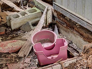 Bathing stool and bowl on rotten floor in Motel Sun River