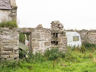 old caravan behind abandoned house